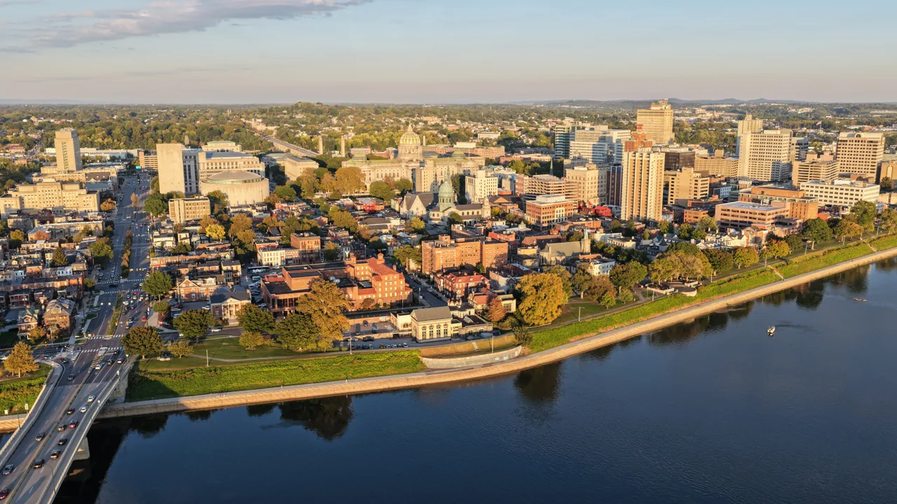 Downtown Harrisburg and its tree-lined waterfront seen diagonally across the Susquehanna