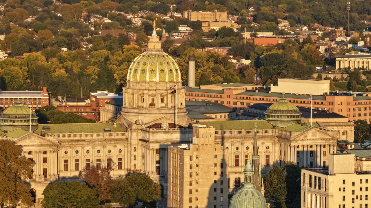 The green dome and stone facade of the Pennsylvania State Capitol in warm evening light