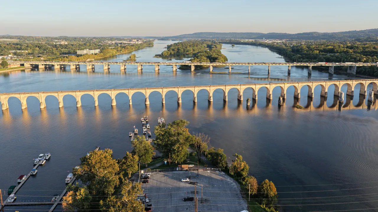 A long stone arch bridge crossing the Susquehanna River with wooded islands beyond