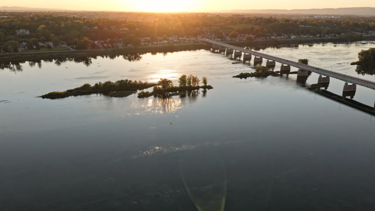 Sunset reflected in the Susquehanna River beside a bridge and small wooded islands